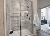 Thumbnail 10 of 36 - A modern bathroom with a glass shower enclosure and a white towel hanging on the door.