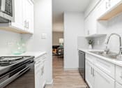 Thumbnail 6 of 17 - A kitchen with white cabinets and a stove top oven.