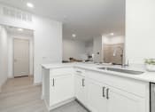 Thumbnail 11 of 35 - a large white kitchen with white cabinets and a sink