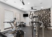 Thumbnail 26 of 32 - a gym with cardio machines and a tv