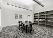 Thumbnail 9 of 14 - A room with a table and chairs and a shelf with books.