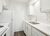 Thumbnail 1 of 21 - A white kitchen with a white fridge and white cabinets.