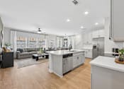 Thumbnail 7 of 37 - A modern kitchen with a large island and a living area with a couch.