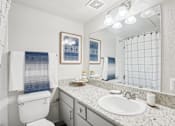 Thumbnail 14 of 40 - A bathroom with a toilet, sink, and mirror.