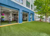 Thumbnail 5 of 19 - a home gym with a green lawn and a building with blue doors