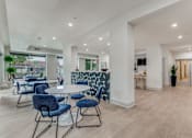 Thumbnail 2 of 19 - A modern dining room with a white table and blue chairs.