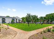 Thumbnail 15 of 19 - a park with a playground and a building in the background
