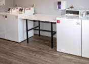 Thumbnail 15 of 16 - a laundry room with four washing machines and a table