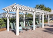 Thumbnail 19 of 30 - A patio with a white pergola and green chairs.