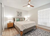 Thumbnail 8 of 17 - A bedroom with a bed, nightstand, and a ceiling fan.