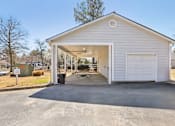 Thumbnail 11 of 31 - A white garage with a door open and a trash can in front.