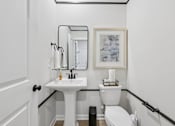 Thumbnail 16 of 37 - A bathroom with a toilet, sink, and mirror.