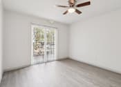 Thumbnail 26 of 38 - A room with a ceiling fan and sliding glass doors leading to a balcony.