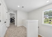 Thumbnail 19 of 37 - A white room with a window and a door leading to another room.