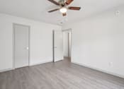 Thumbnail 23 of 38 - A room with a ceiling fan and wooden flooring.