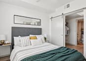Thumbnail 11 of 26 - A bedroom with a bed, nightstand, and a mirror above the bed.