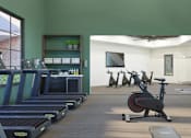 Thumbnail 27 of 37 - A room with exercise equipment and a television.