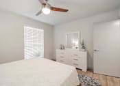 Thumbnail 13 of 17 - A white bedroom with a bed, dresser, mirror, and a ceiling fan.