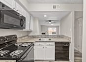 Thumbnail 39 of 54 - A kitchen with a black stove top oven and white cabinets.