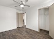 Thumbnail 28 of 43 - A room with a ceiling fan and wood flooring.