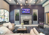 Thumbnail 7 of 25 - A living room with a fireplace and a flat screen TV mounted above it.