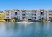 Thumbnail 1 of 30 - A large apartment complex with a fountain in front.