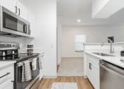 Thumbnail 23 of 41 - a renovated kitchen with stainless steel appliances and white cabinets