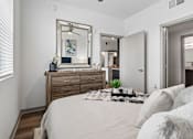 Thumbnail 12 of 34 - A bedroom with a large bed, a wooden dresser, and a mirror above it.
