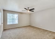 Thumbnail 11 of 16 - an empty living room with a ceiling fan and a window