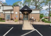 Thumbnail 16 of 16 - a brick building with a black awning and stairs in front of a driveway