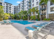 Thumbnail 15 of 25 - a swimming pool with chaise lounge chairs in front of an apartment building