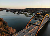 Thumbnail 17 of 30 - A bridge spans a river with cars driving on it.