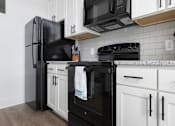 Thumbnail 7 of 11 - A black refrigerator stands next to a black oven in a kitchen.