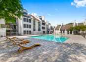 Thumbnail 21 of 28 - a swimming pool with chaise lounge chairs and buildings in the background