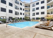 Thumbnail 23 of 37 - a swimming pool with chaise lounge chairs and an apartment building in the background