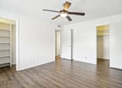 Thumbnail 3 of 21 - A room with a ceiling fan and wooden flooring.
