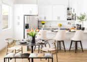 Thumbnail 3 of 30 - a dining area with a table and chairs and a kitchen in the background
