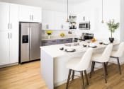 Thumbnail 2 of 30 - a kitchen with white cabinets and a white island with three white chairs