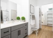 Thumbnail 22 of 30 - a bathroom with gray cabinets and a white countertop with two green plants on top of it