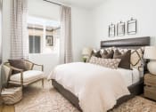 Thumbnail 6 of 30 - a bedroom with a large bed and a chair in front of a window