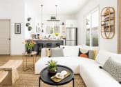 Thumbnail 19 of 30 - a living room with a white couch and a kitchen in the background