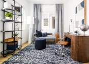 Thumbnail 5 of 30 - a living room with a blue rug and a desk with a chair and a couch in the