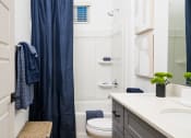 Thumbnail 24 of 30 - a bathroom with white walls and a blue shower curtain