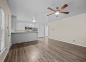 Thumbnail 5 of 11 - an empty living room with a ceiling fan and a kitchen