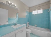 Thumbnail 10 of 11 - a bathroom with blue tile and a white toilet and sink