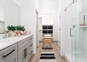 Thumbnail 6 of 19 - A bathroom with a white counter and a glass shower stall.