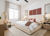 Thumbnail 10 of 20 - A bedroom with a large bed, a chair, a side table, and a ceiling fan.