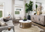 Thumbnail 3 of 20 - A living room with a grey couch, a round coffee table, and a large plant.