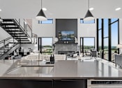 Thumbnail 16 of 35 - A modern kitchen with a stainless steel countertop and a television above it.