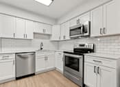 Thumbnail 4 of 10 - a white kitchen with stainless steel appliances and white cabinets